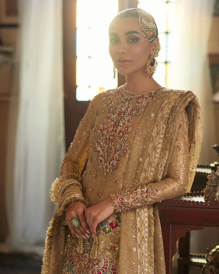 Model wearing a golden Gurleen dress with intricate red embroidery from Faiza Saqlain's Formals Sanaz collection, showcasing Pakistani clothes online in the UK.