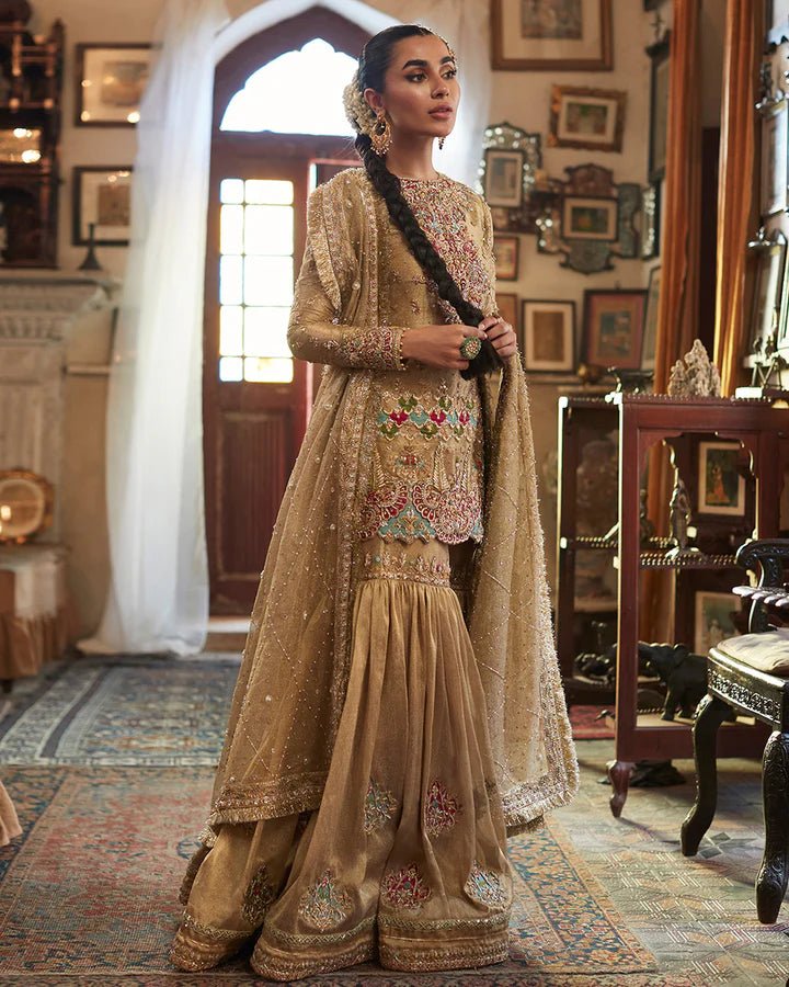 Model wearing a golden Gurleen dress with intricate red embroidery from Faiza Saqlain's Formals Sanaz collection, showcasing Pakistani clothes online in the UK.