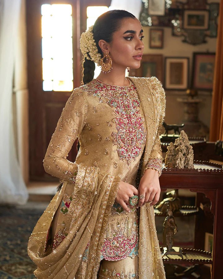 Model wearing a golden Gurleen dress with intricate red embroidery from Faiza Saqlain's Formals Sanaz collection, showcasing Pakistani clothes online in the UK.