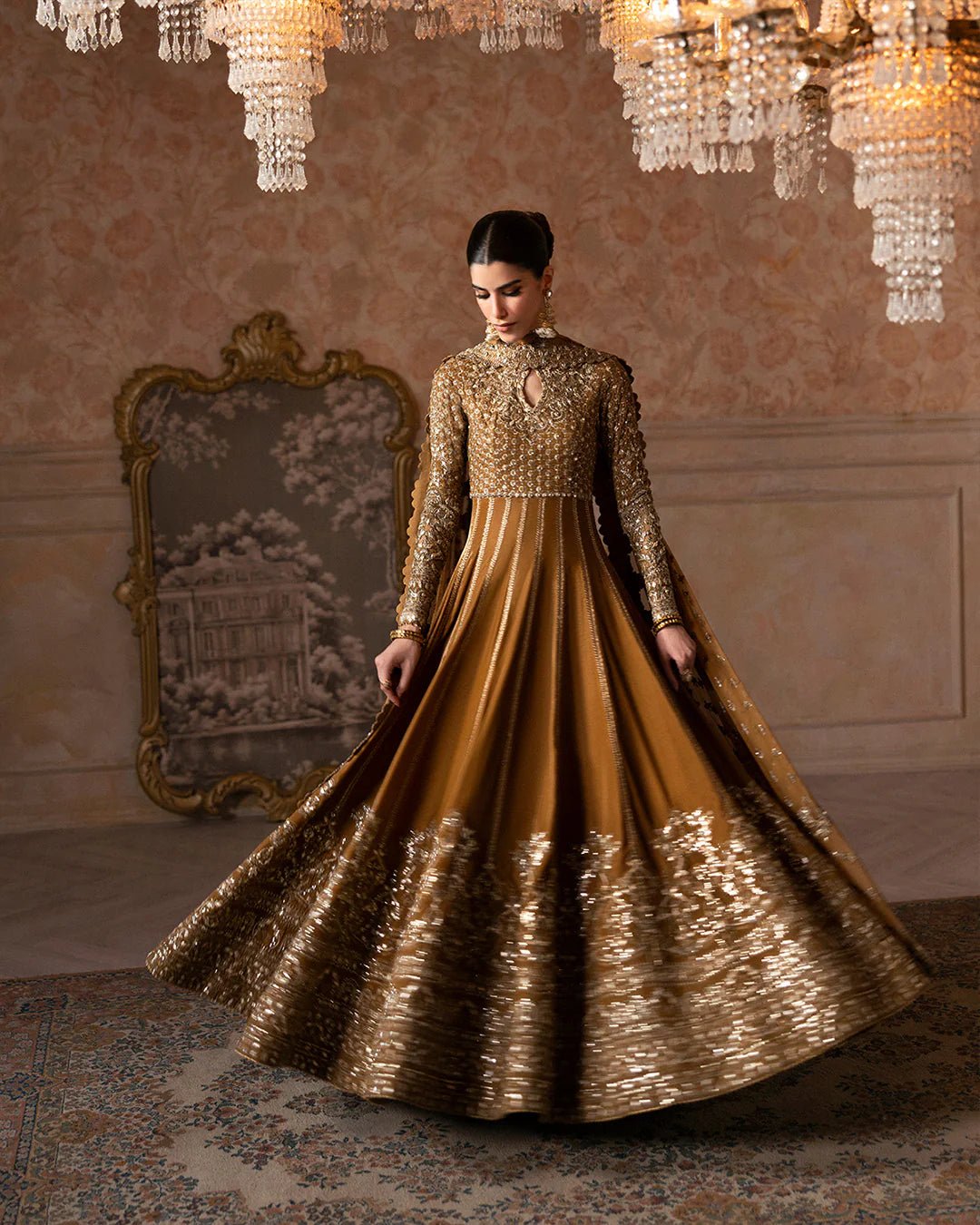 Model wearing Faiza Saqlain Ismene Velvet Ermina dress in antique gold with intricate silver embroidery. Shop Pakistani bridal dresses online in the UK now.