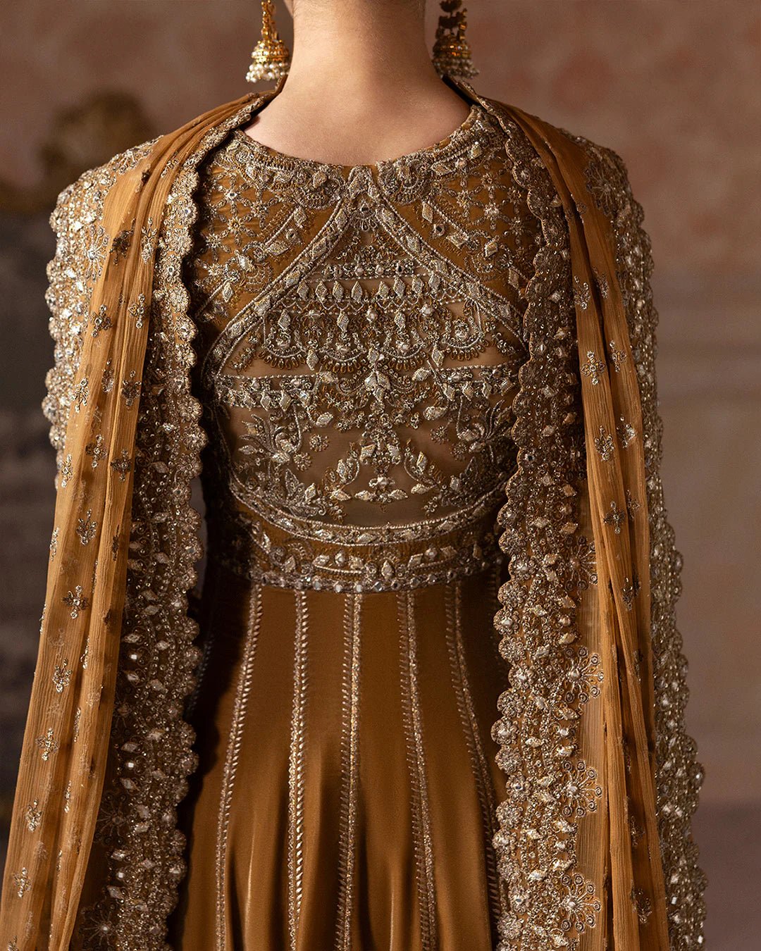 Model wearing Faiza Saqlain Ismene Velvet Ermina dress in antique gold with intricate silver embroidery. Shop Pakistani bridal dresses online in the UK now.