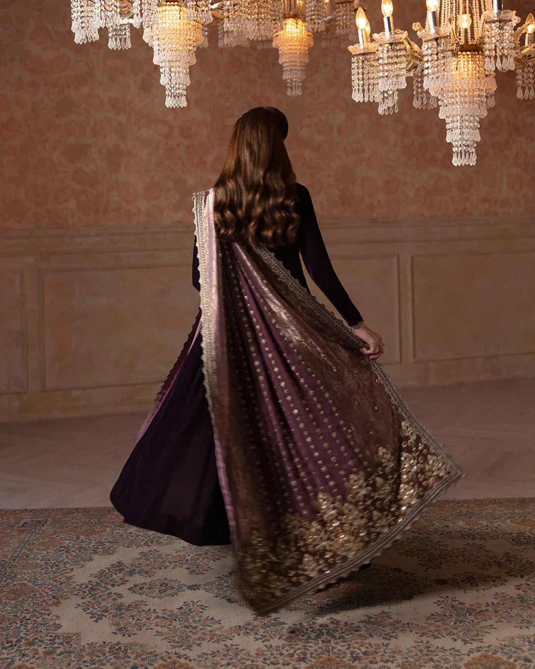 Model wearing Faiza Saqlain Ismene Velvet Erna dress in deep plum with intricate gold embroidery and an embellished dupatta. Shop Pakistani bridal dresses online in the UK now.