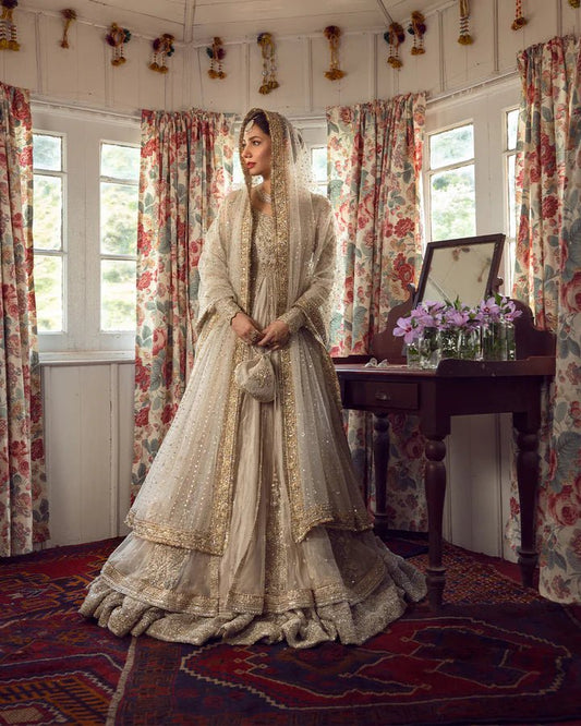 Model wearing Faiza Saqlain Anamta dress in ivory, adorned with delicate embellishments, perfect for Pakistani nikkah bridal wear available online in the UK.