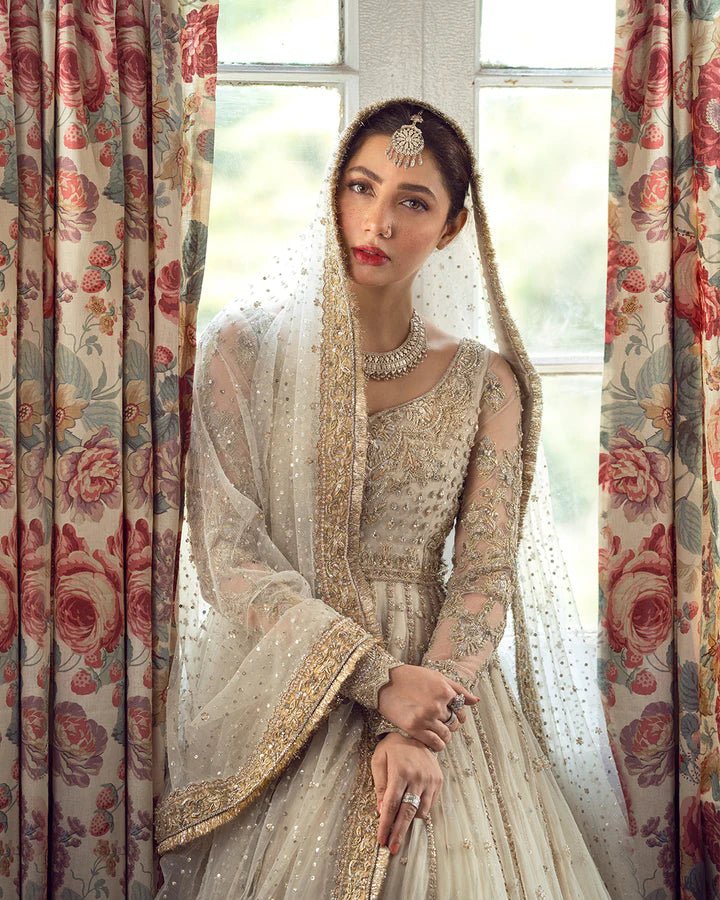 Model wearing Faiza Saqlain Anamta dress in ivory, adorned with delicate embellishments, perfect for Pakistani nikkah bridal wear available online in the UK.