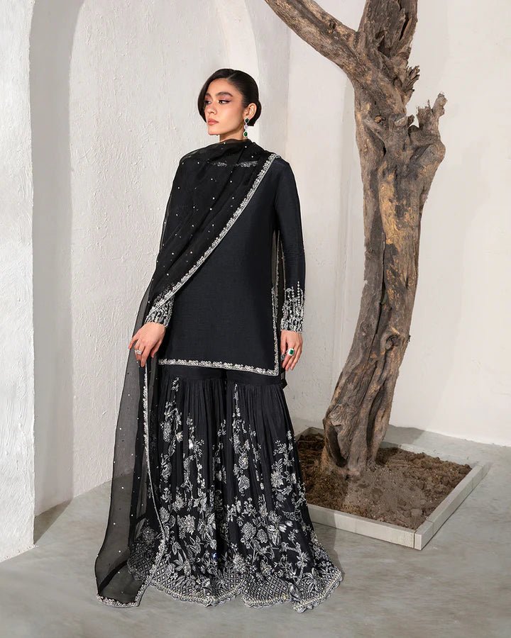 model wearing Faiza Saqlain Ciar Pakistani formal dress in UK, elegant black with silver embroidery