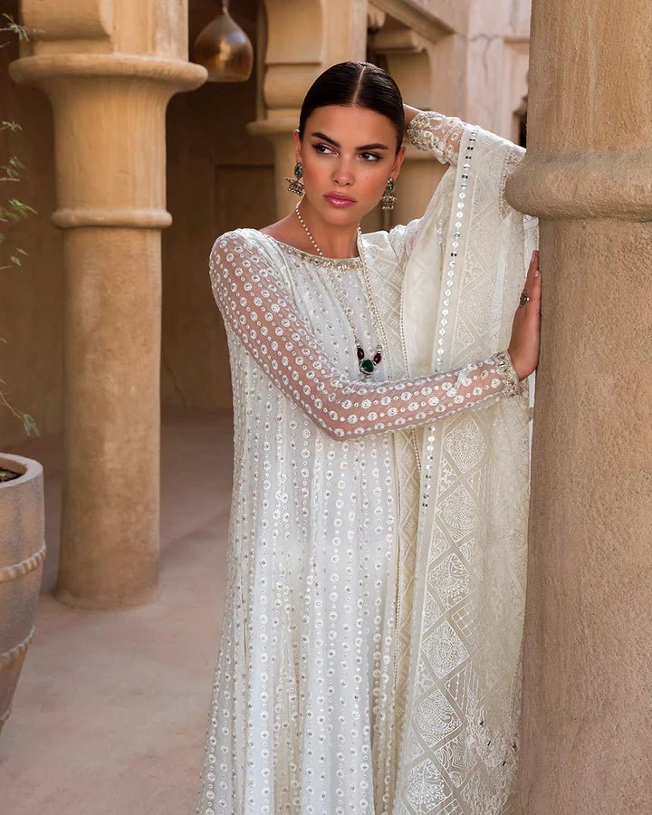 Model wearing an elegant white Aysel dress adorned with intricate detailing from Faiza Saqlain's Luxe Formals Laira collection. Pakistani clothes online in UK.