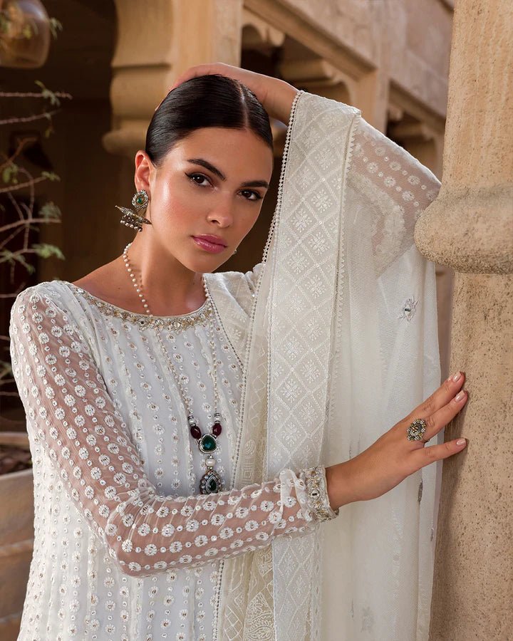 Model wearing an elegant white Aysel dress adorned with intricate detailing from Faiza Saqlain's Luxe Formals Laira collection. Pakistani clothes online in UK.