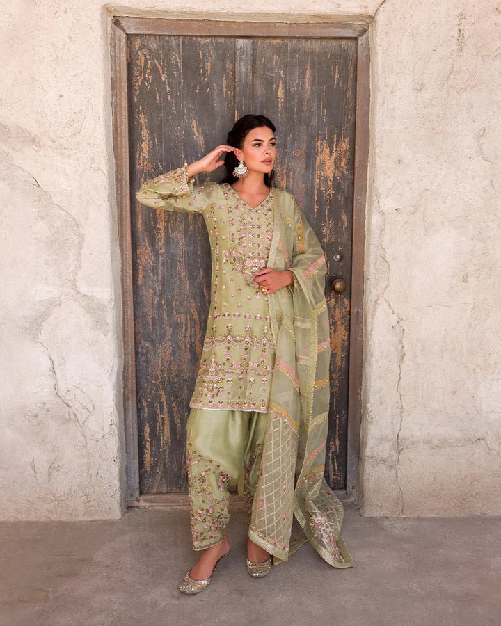 Model wearing a delicate green Noya dress adorned with floral embroidery from Faiza Saqlain's Luxe Formals Laira collection. Pakistani clothes online in UK.