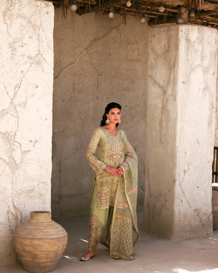 Model wearing a delicate green Noya dress adorned with floral embroidery from Faiza Saqlain's Luxe Formals Laira collection. Pakistani clothes online in UK.