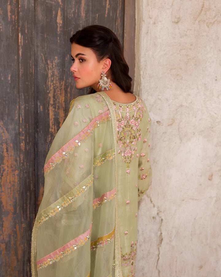 Model wearing a delicate green Noya dress adorned with floral embroidery from Faiza Saqlain's Luxe Formals Laira collection. Pakistani clothes online in UK.