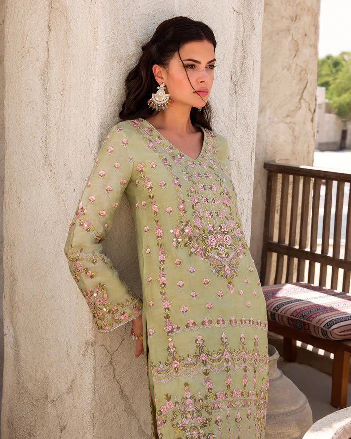 Model wearing a delicate green Noya dress adorned with floral embroidery from Faiza Saqlain's Luxe Formals Laira collection. Pakistani clothes online in UK.