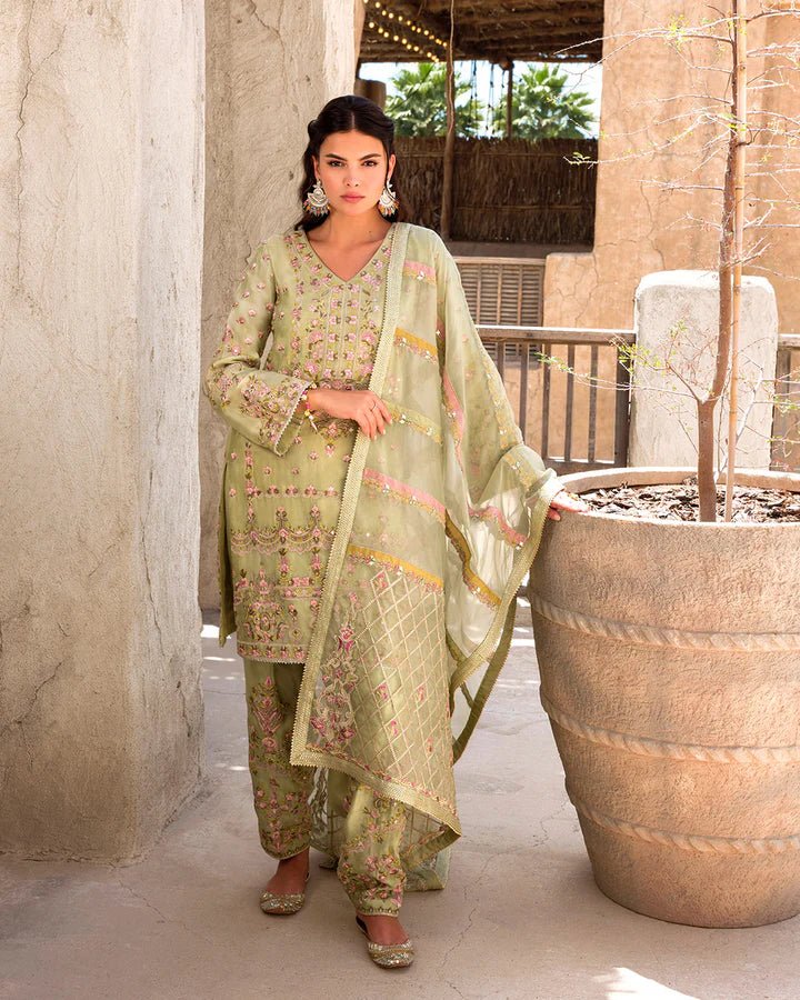 Model wearing a delicate green Noya dress adorned with floral embroidery from Faiza Saqlain's Luxe Formals Laira collection. Pakistani clothes online in UK.