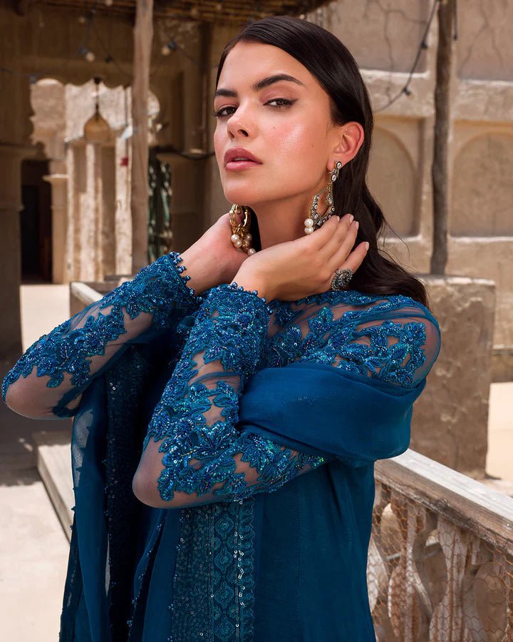 Model wearing a rich blue Nuzar dress by Faiza Saqlain, showcasing exquisite Pakistani fashion available online in the UK.