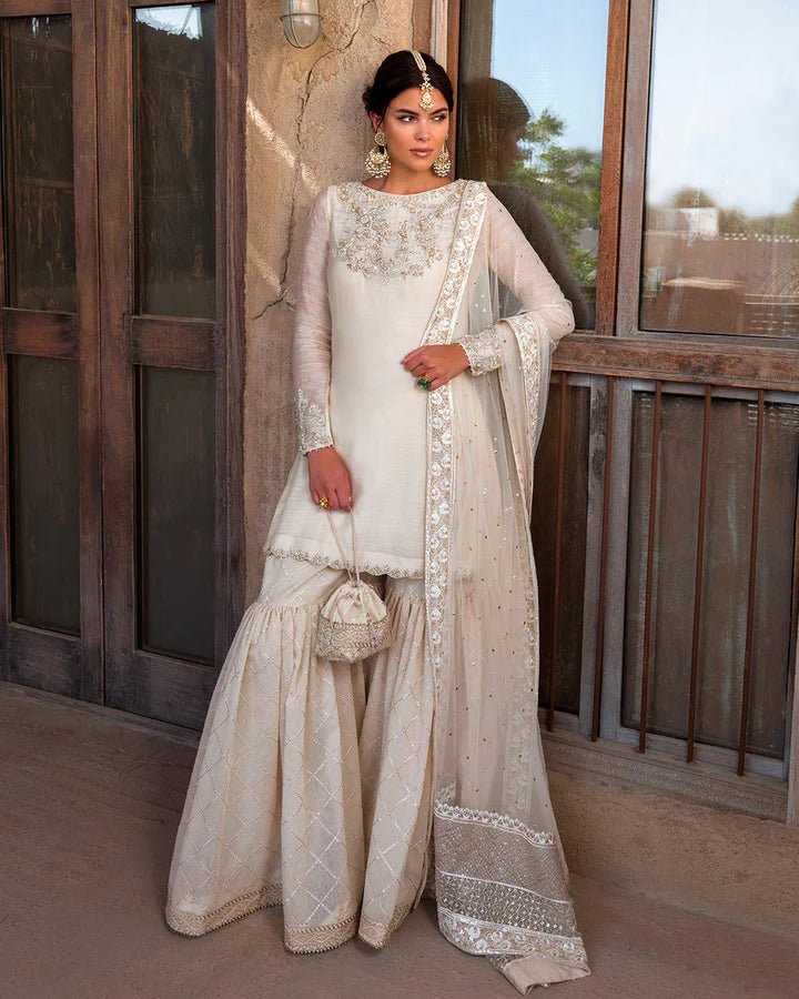 Model wearing an elegant ivory Raabi dress adorned with delicate embroidery from Faiza Saqlain's Luxe Formals Laira collection. Pakistani clothes online in UK.