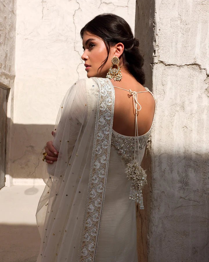 Model wearing an elegant ivory Raabi dress adorned with delicate embroidery from Faiza Saqlain's Luxe Formals Laira collection. Pakistani clothes online in UK.