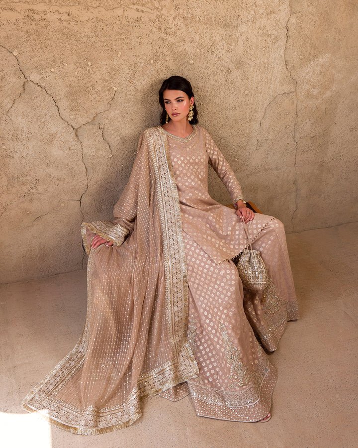 Model wearing a subtle gold Zaain dress by Faiza Saqlain, showcasing elegant Pakistani fashion available online in the UK.