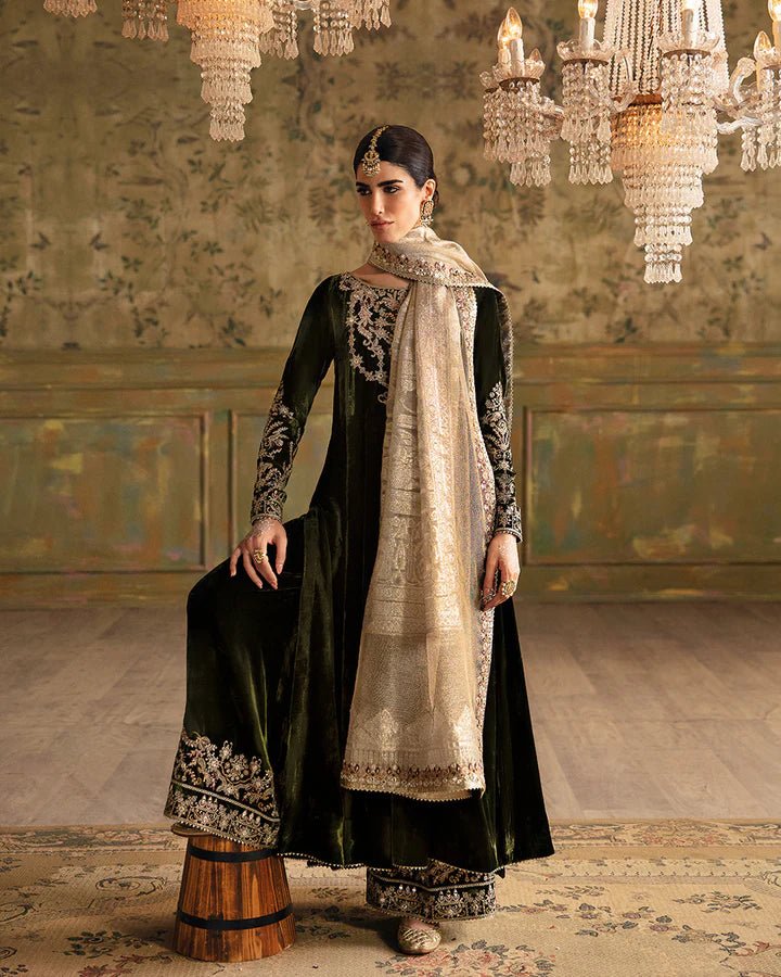 Model wearing a dark green Tissa dress with detailed gold embroidery from Faiza Saqlain's Luxe Formals Manaar Nov '23 collection. Pakistani clothes online in UK.