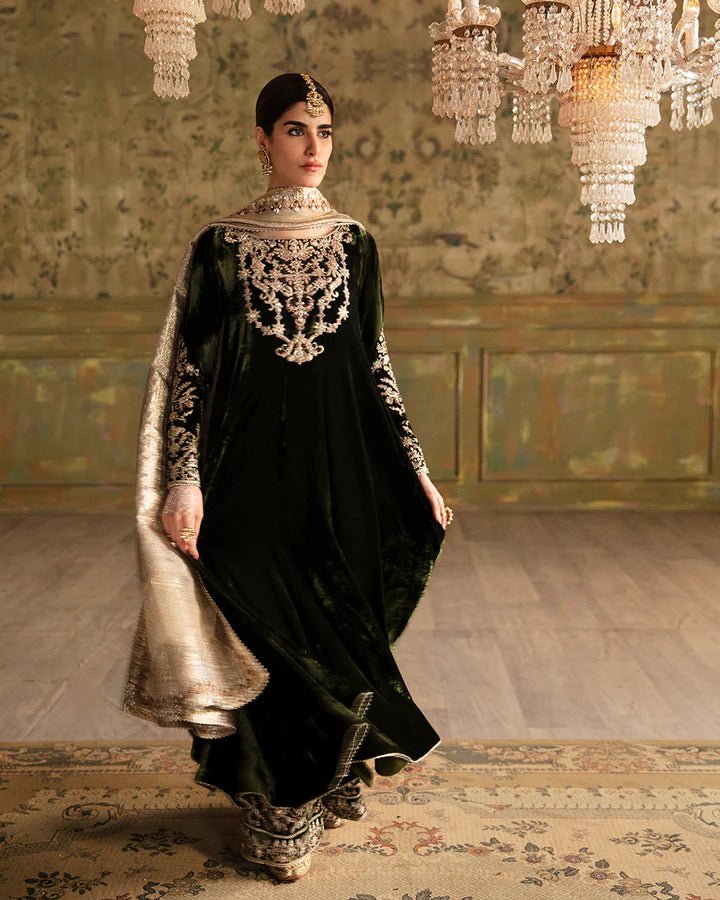 Model wearing a dark green Tissa dress with detailed gold embroidery from Faiza Saqlain's Luxe Formals Manaar Nov '23 collection. Pakistani clothes online in UK.