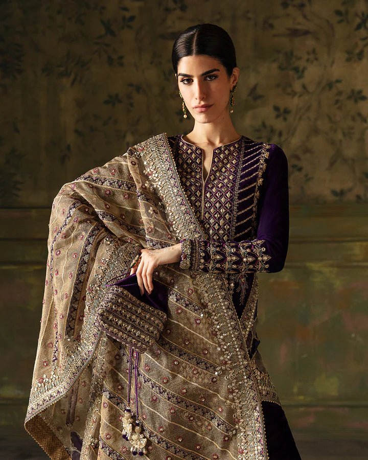 Model wearing a deep purple Elayha dress with intricate gold embroidery from Faiza Saqlain's Luxe Formals Manaar Nov '23 collection. Pakistani clothes online in UK.