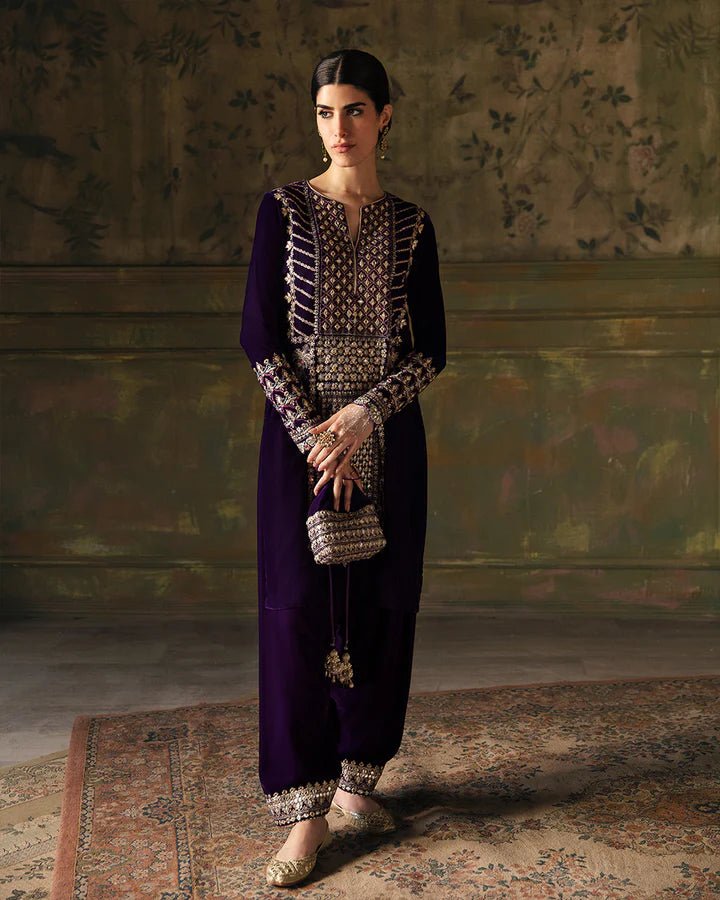 Model wearing a deep purple Elayha dress with intricate gold embroidery from Faiza Saqlain's Luxe Formals Manaar Nov '23 collection. Pakistani clothes online in UK.