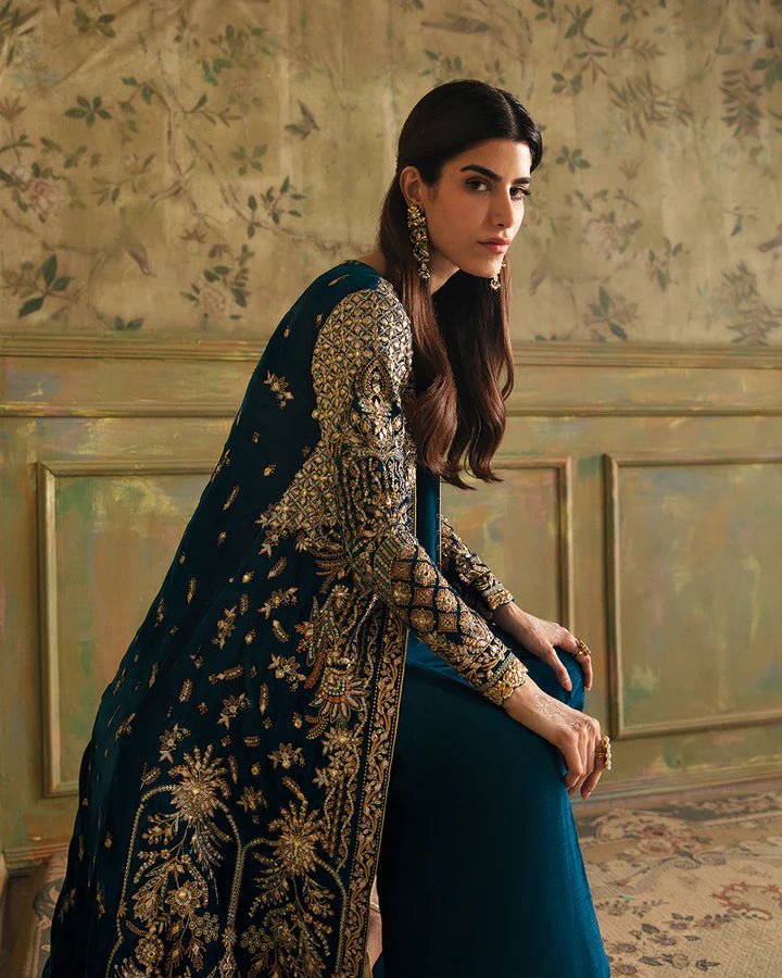 Model wearing a blue Haanie dress with intricate gold embroidery from Faiza Saqlain's Luxe Formals Manaar Nov '23 collection. Pakistani clothes online in UK.