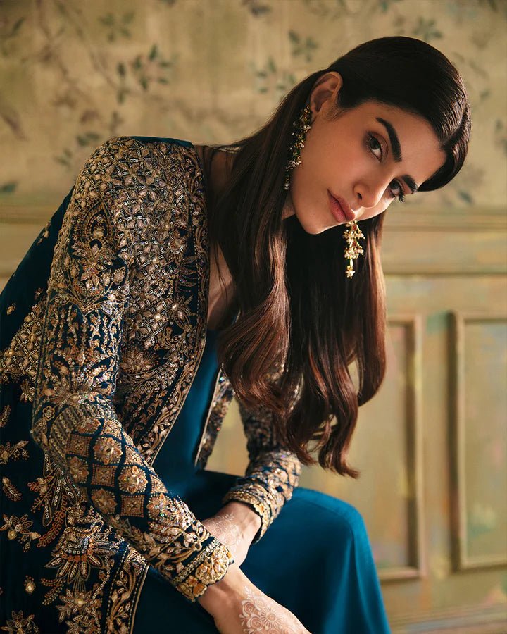 Model wearing a blue Haanie dress with intricate gold embroidery from Faiza Saqlain's Luxe Formals Manaar Nov '23 collection. Pakistani clothes online in UK.