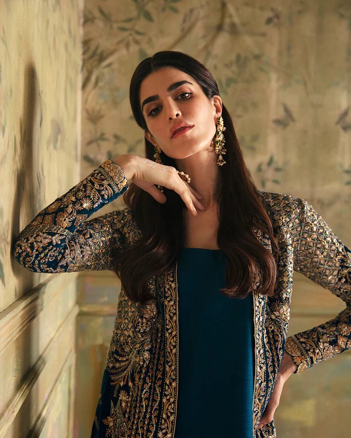 Model wearing a blue Haanie dress with intricate gold embroidery from Faiza Saqlain's Luxe Formals Manaar Nov '23 collection. Pakistani clothes online in UK.