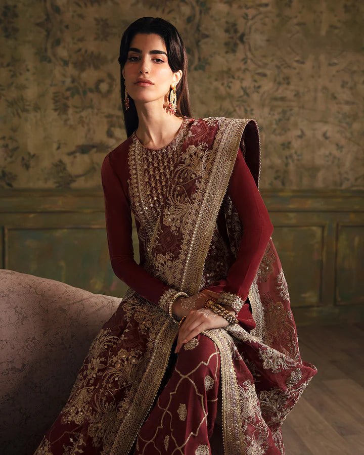 Model wearing a maroon Negar dress with intricate gold embroidery from Faiza Saqlain's Luxe Formals Manaar Nov '23 collection. Pakistani clothes online in UK.