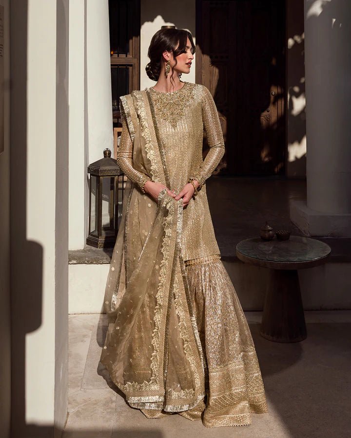 Model wearing a gold Linia dress with intricate embellishments from Faiza Saqlain's Aleira Evening Edit '24 collection. Pakistani clothes online in UK.