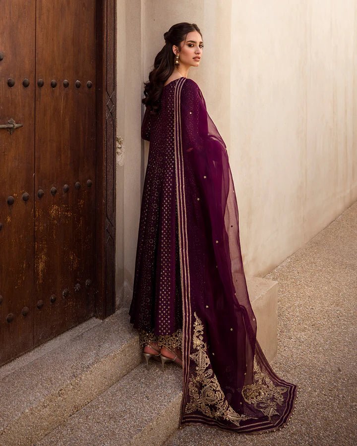 Model wearing a deep purple Yashal dress adorned with golden embroidery from Faiza Saqlain's Luxe Formals Noor e Chashm collection. Pakistani clothes online in UK.