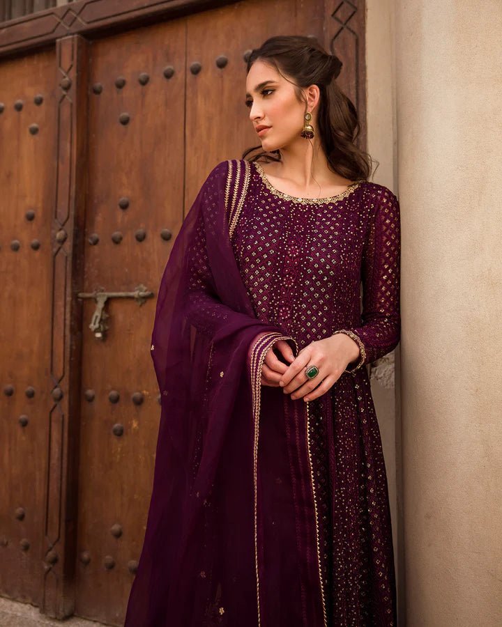 Model wearing a deep purple Yashal dress adorned with golden embroidery from Faiza Saqlain's Luxe Formals Noor e Chashm collection. Pakistani clothes online in UK.