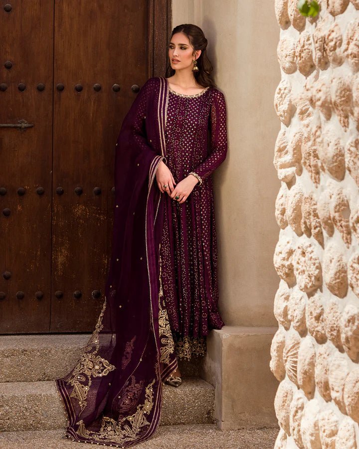 Model wearing a deep purple Yashal dress adorned with golden embroidery from Faiza Saqlain's Luxe Formals Noor e Chashm collection. Pakistani clothes online in UK.