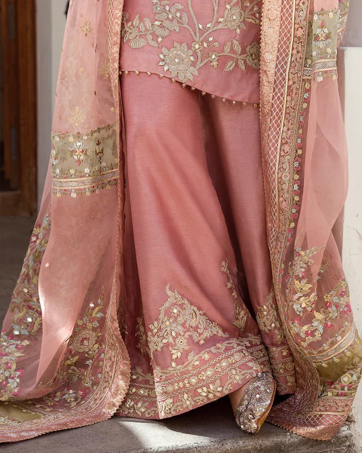 Model wearing a peach Marissa dress adorned with intricate gold embroidery from Faiza Saqlain's Luxe Formals Noor e Chashm collection. Pakistani clothes online in UK.