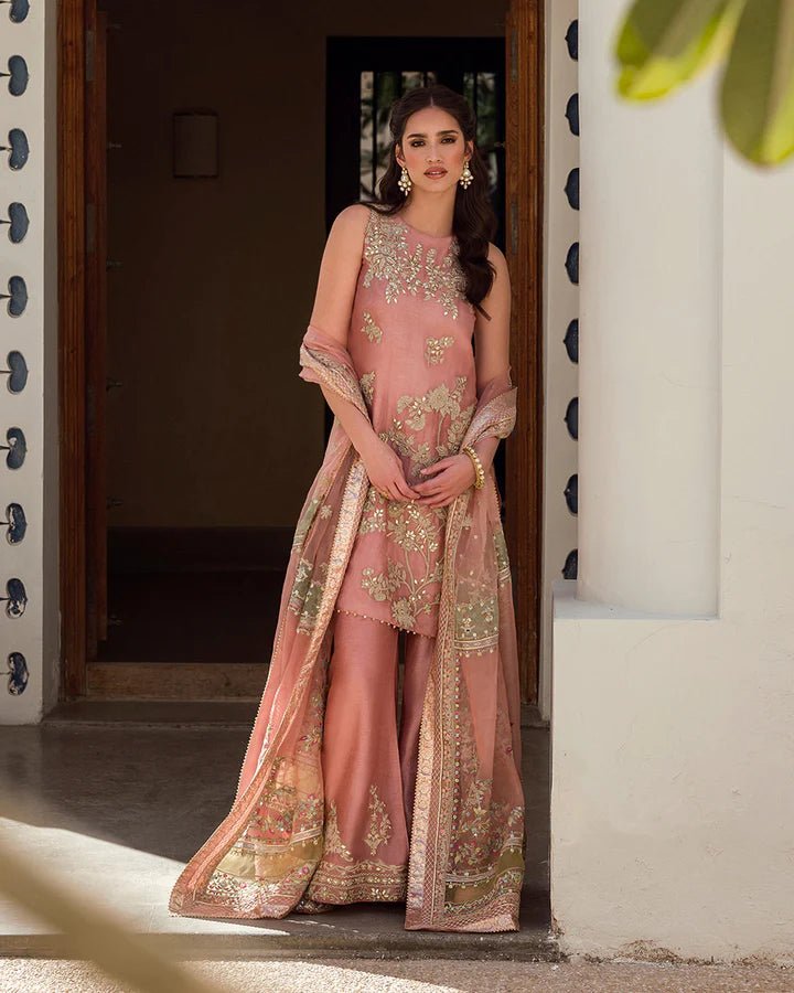 Model wearing a peach Marissa dress adorned with intricate gold embroidery from Faiza Saqlain's Luxe Formals Noor e Chashm collection. Pakistani clothes online in UK.