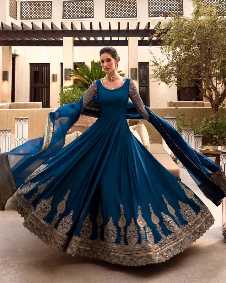 Model wearing a royal blue Risma dress embellished with intricate silver motifs from Faiza Saqlain's Luxe Formals Noor e Chashm collection. Pakistani clothes online in UK.