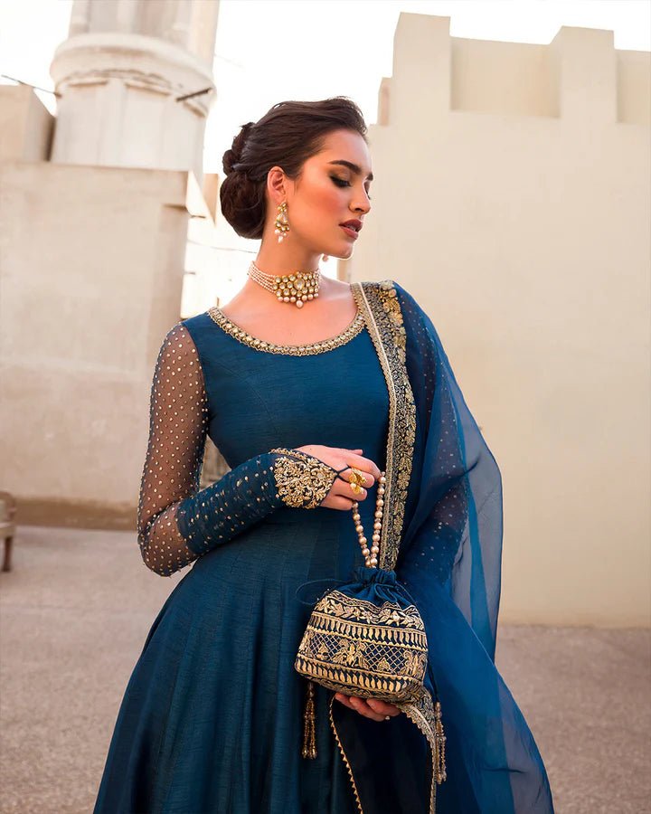 Model wearing a royal blue Risma dress embellished with intricate silver motifs from Faiza Saqlain's Luxe Formals Noor e Chashm collection. Pakistani clothes online in UK.