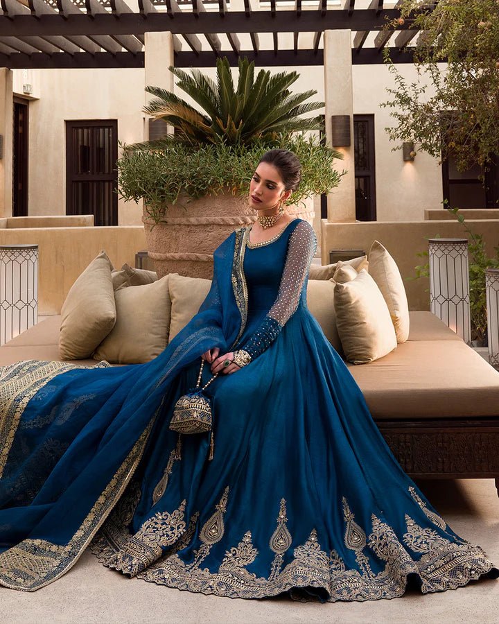 Model wearing a royal blue Risma dress embellished with intricate silver motifs from Faiza Saqlain's Luxe Formals Noor e Chashm collection. Pakistani clothes online in UK.