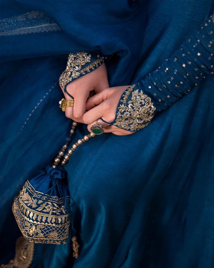 Model wearing a royal blue Risma dress embellished with intricate silver motifs from Faiza Saqlain's Luxe Formals Noor e Chashm collection. Pakistani clothes online in UK.