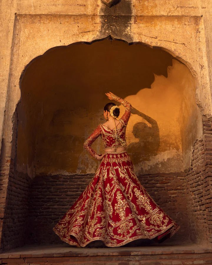 Model wearing a red Arusa bridal dress from Faiza Saqlain, intricately embroidered with gold detailing. Perfect for luxury bridal wear, available online in the UK.