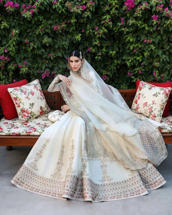 Model wearing an ivory Ailia dress from Faiza Saqlain's Mehermah Luxe Formals '24 collection. Pakistani clothes online in UK, wedding clothes.