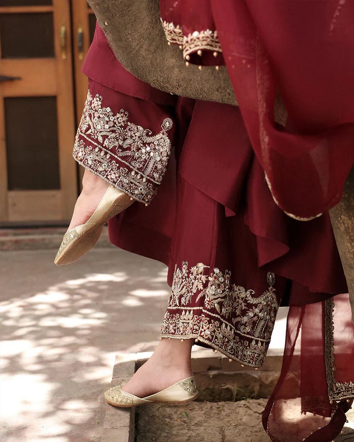 Model wearing a maroon dress with intricate gold embroidery, from Faiza Saqlain's Mehermah Luxe Formals '24 collection, highlighting Pakistani clothes online in UK and wedding clothes.