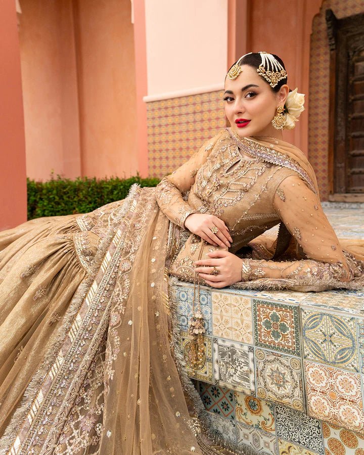 Model wearing a gold Jolina dress from Faiza Saqlain's Neorah Wedding Festive '24 Collection, featuring intricate embroidery and a flowing silhouette. Pakistani wedding clothes available online in the UK.