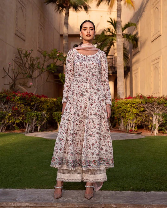 Model wearing the Elysia dress from Faiza Saqlain’s Zurina Luxe Silk Edit 2024, in beige with delicate floral prints. Pakistani designer clothes available in the UK. Perfect for Eid dresses.