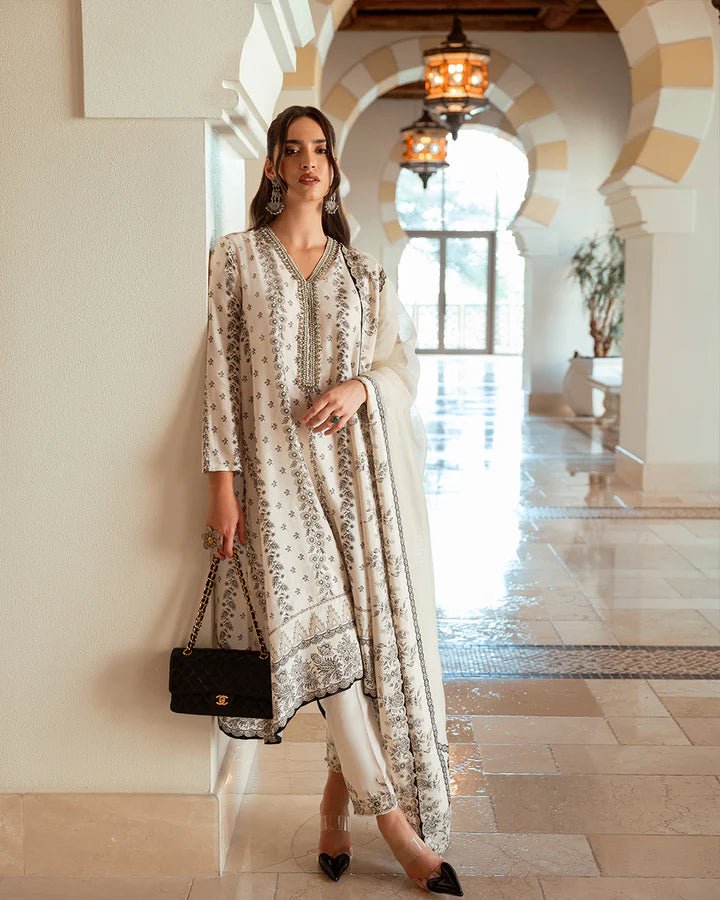 Model wearing white Mireya dress with intricate black embroidery from Faiza Saqlain's Zurina Luxe Silk Edit '24 collection. Pakistani clothes online in UK.