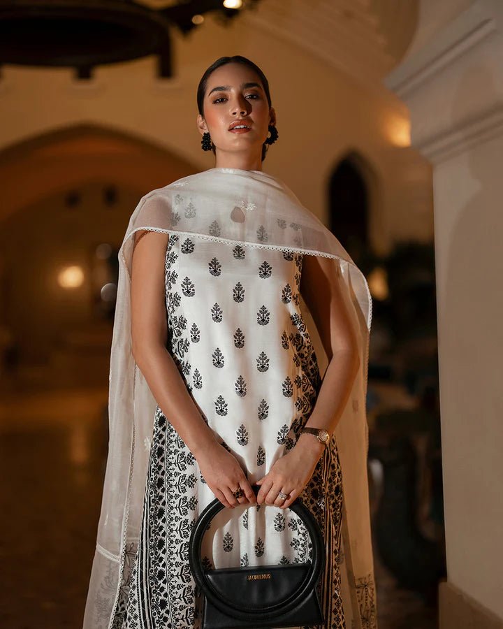 Model wearing a white Zita dress with black embroidery from Faiza Saqlain's Zurina Luxe Silk Edit '24 collection. Pakistani clothes online in UK.