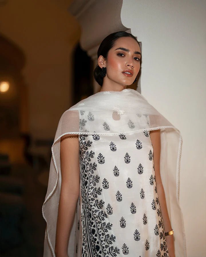 Model wearing a white Zita dress with black embroidery from Faiza Saqlain's Zurina Luxe Silk Edit '24 collection. Pakistani clothes online in UK.