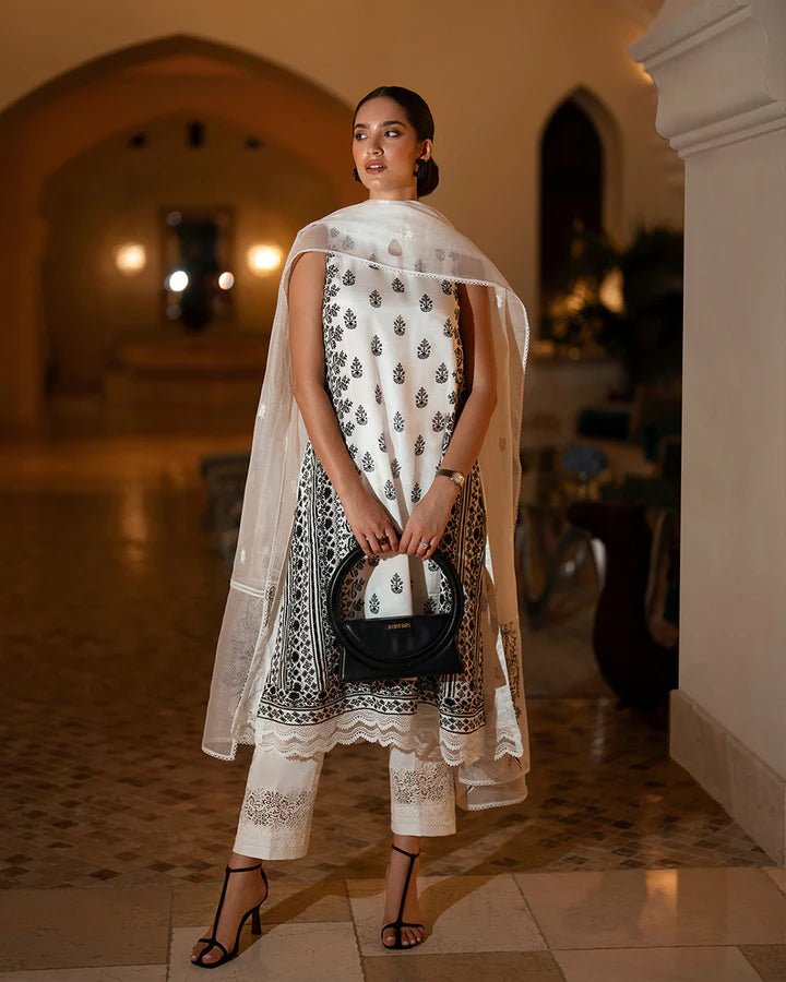 Model wearing a white Zita dress with black embroidery from Faiza Saqlain's Zurina Luxe Silk Edit '24 collection. Pakistani clothes online in UK.