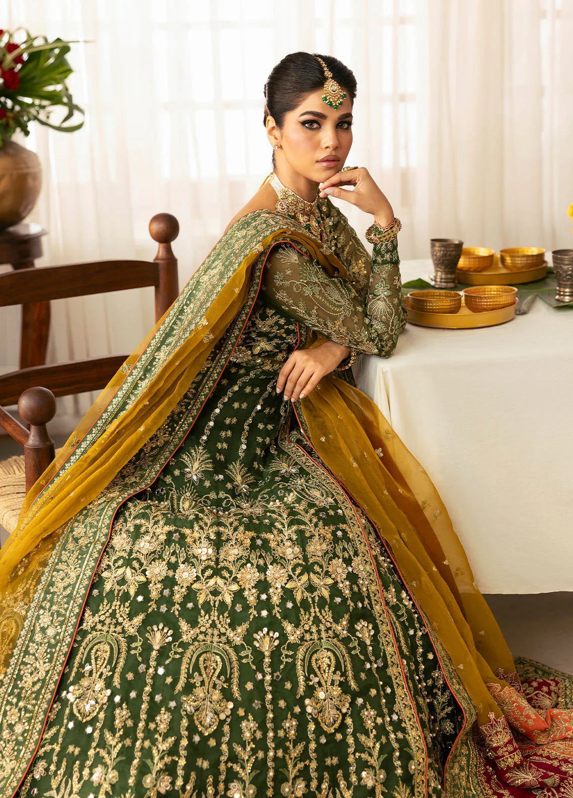 Model wearing Gulaal Maahru deep green and mustard embroidered wedding lehenga with intricate embellishments and contrasting dupatta. Shop Pakistani clothes online in the UK now.