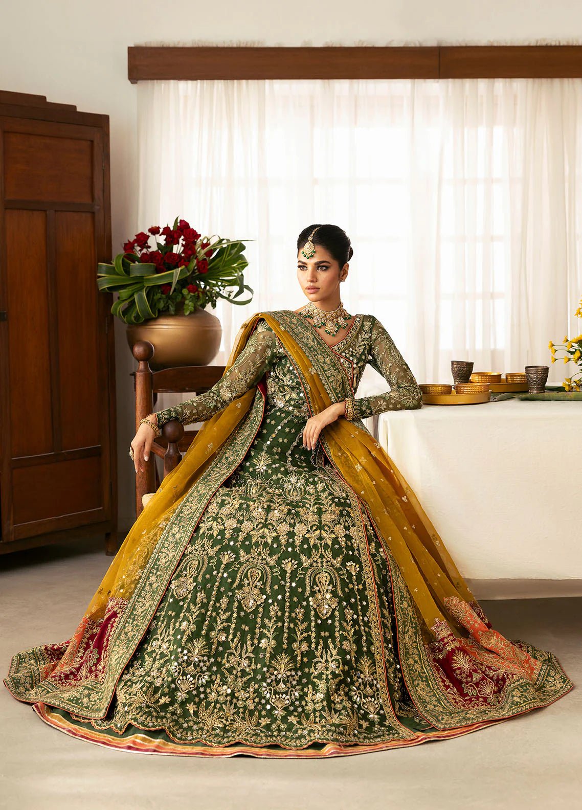 Model wearing Gulaal Maahru deep green and mustard embroidered wedding lehenga with intricate embellishments and contrasting dupatta. Shop Pakistani clothes online in the UK now.