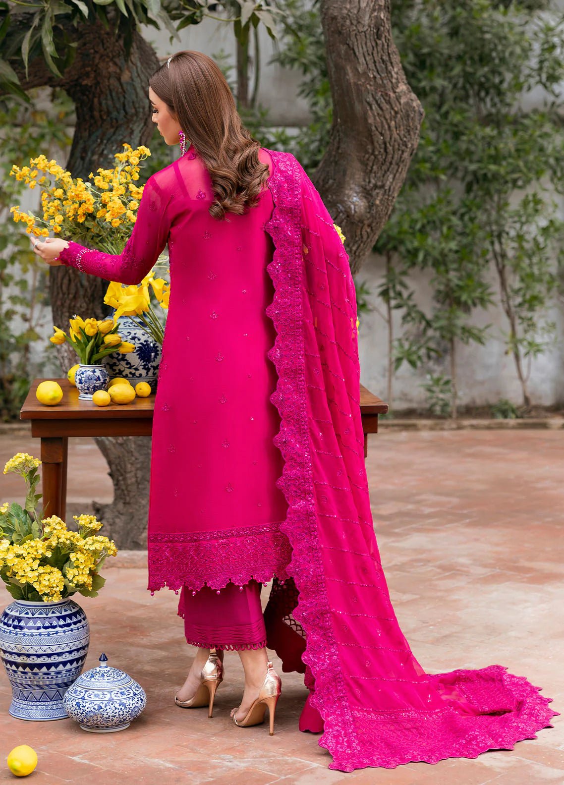 Model wearing Gulaal Zevira hot pink embroidered chiffon dress with matching dupatta and trousers. Shop Pakistani clothes online in the UK now.